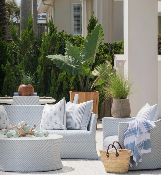 Cushioned patio lounge seating with striped pillows surrounded by tropical greenery