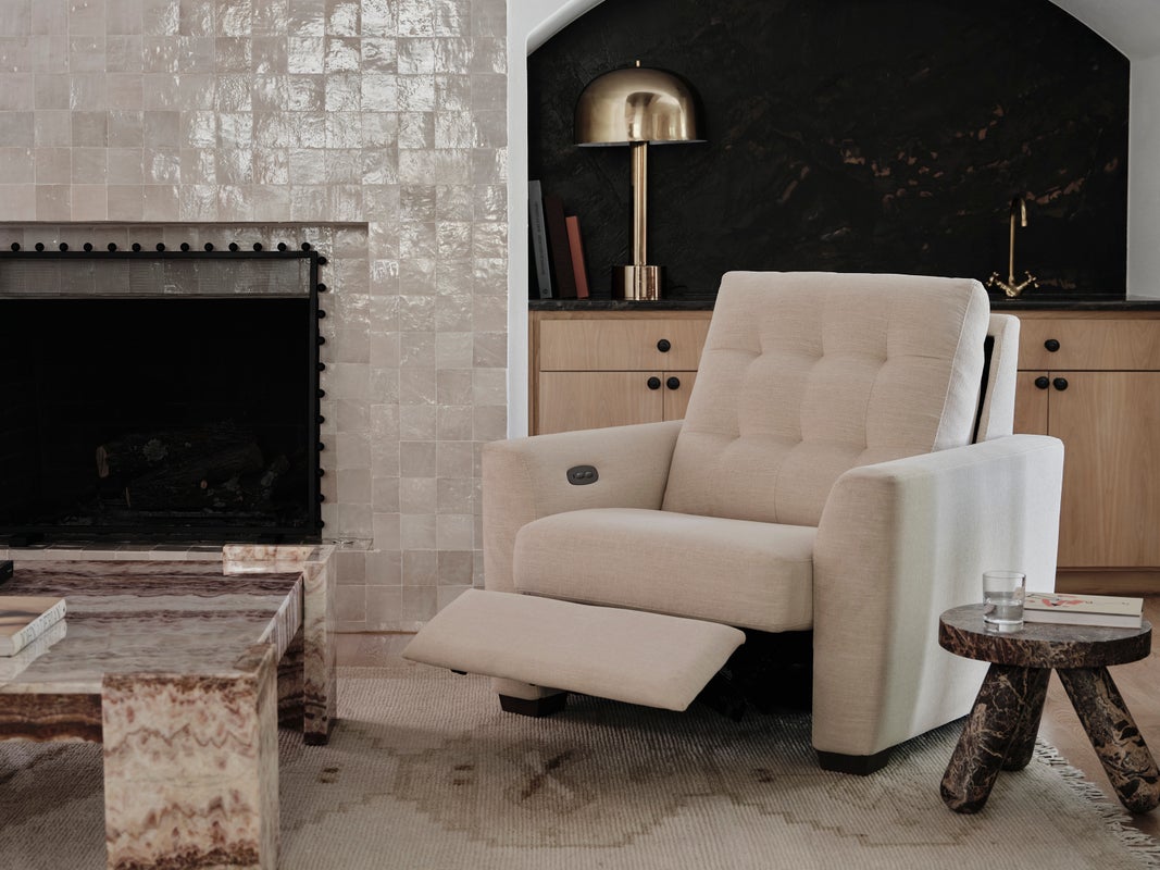 Upholstered power recliner positioned beside a fireplace in a relaxed media room